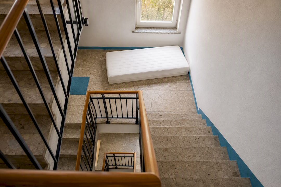Matratze liegt auf dem Treppenabsatz in einem Mehrfamilienhaus